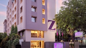 Um hotel moderno com um logo 'Z' em destaque, vários andares e uma entrada bem iluminada.