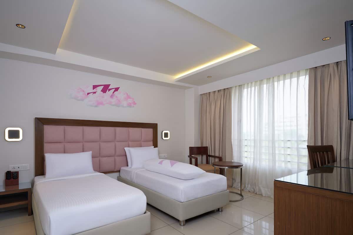 A hotel room with two beds, a desk, a chair, a TV, and a decorative wall piece.