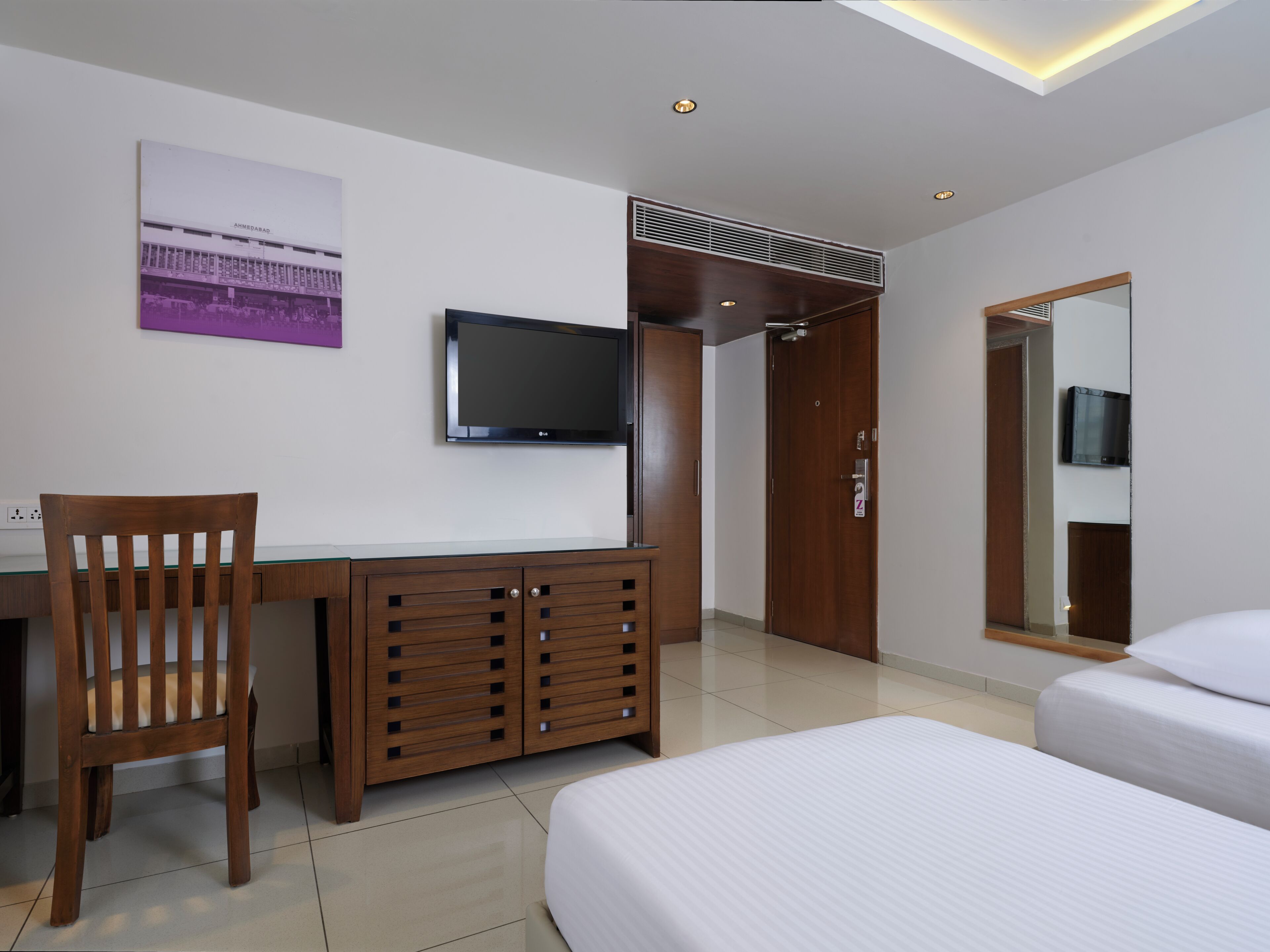 Una habitación de hotel con cama, escritorio, televisor y armario.