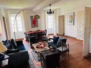A spacious living room with a dining area, wooden flooring, and a large window. - Charming apartment in Sartène, South Corsica, terrace with panoramic view (Sartène)
