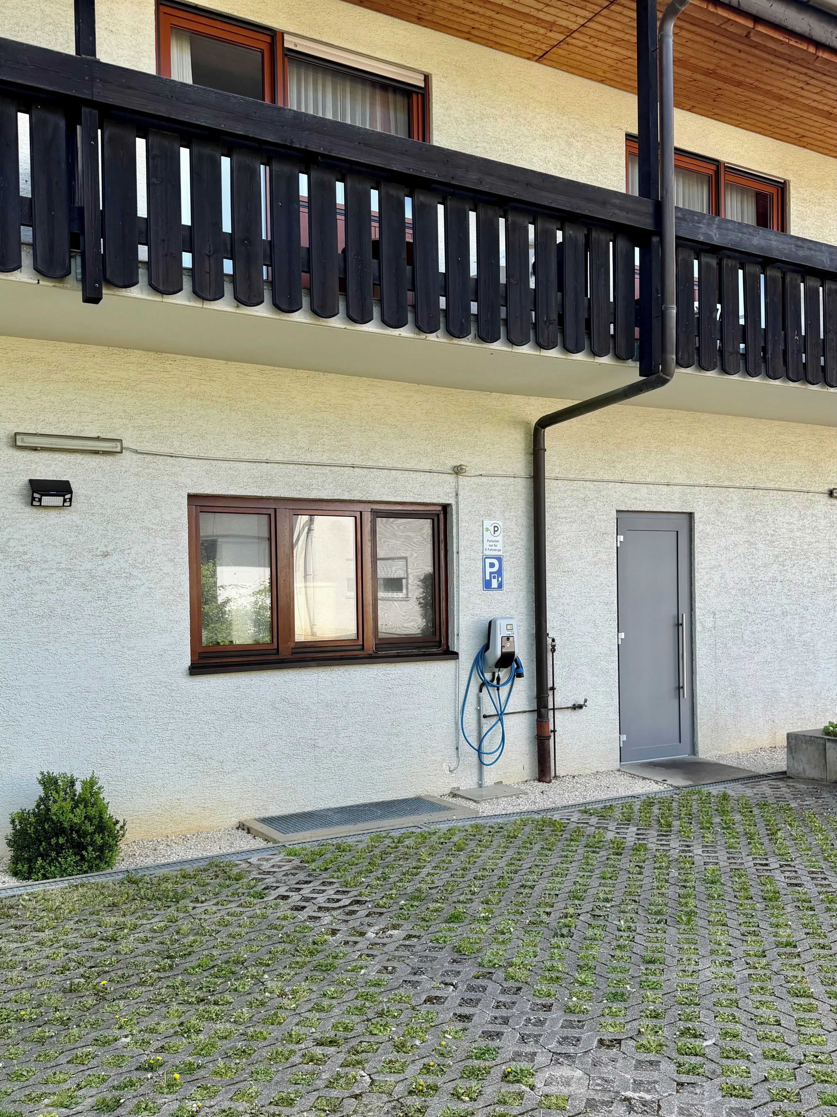 A building with a balcony, a door, a window, and a parking sign.
