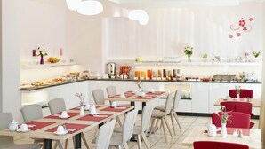 A modern dining area with tables set for service, a kitchen in the background, and a clean, minimalist decor. - Hotel am Buchwald (Esslingen)