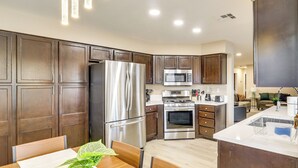 Una cocina moderna con electrodomésticos de acero inoxidable, armarios de madera y un comedor con mesa y sillas.
