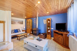 Una sala de estar con sofá, mesa de centro, televisión, chimenea y armarios de madera.