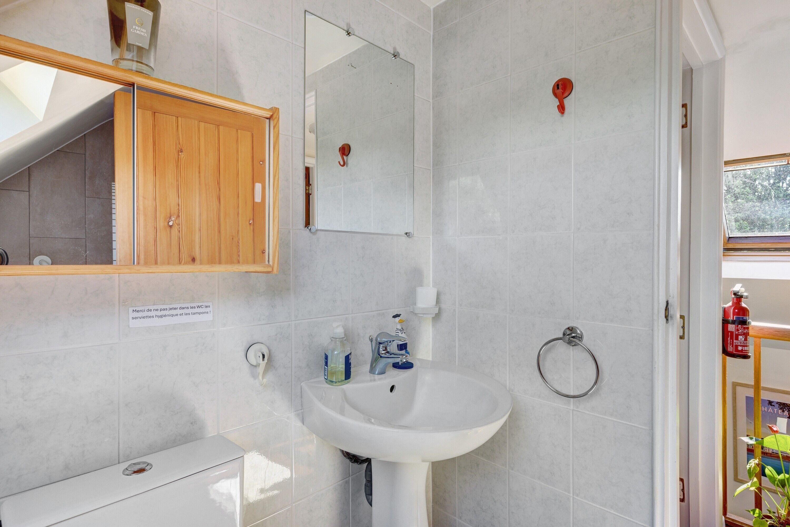 Een badkamer met een witte wasbak, spiegel en houten kastje.