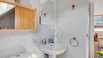 Een badkamer met een witte wasbak, spiegel en houten kastje.