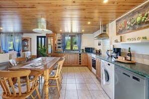 Una cocina con armarios de madera, lavadora y comedor con mesa y sillas.
