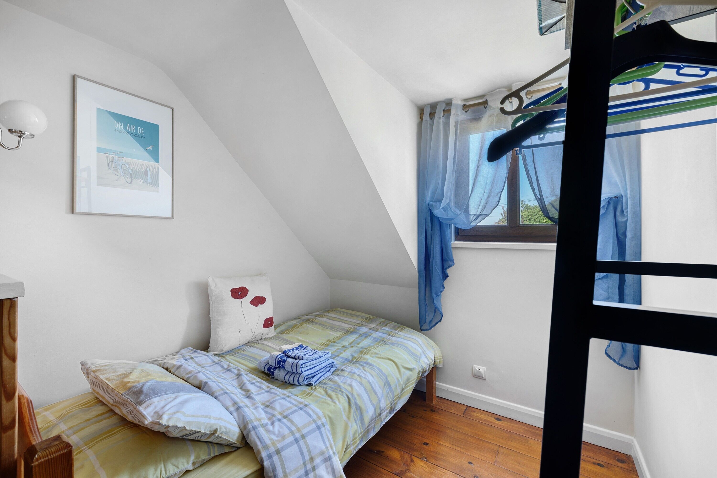 Ein Schlafzimmer mit einem Etagenbett, einem gerahmten Bild an der Wand und einem Fenster mit Vorhängen.