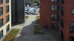 A multi-story building with a parking lot, a grassy area, and a clear sky with clouds. - Luxury 2BR Apartment - Free parking (Slough)