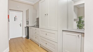Een keuken met witte kastjes, een magnetron en een spoelbak.