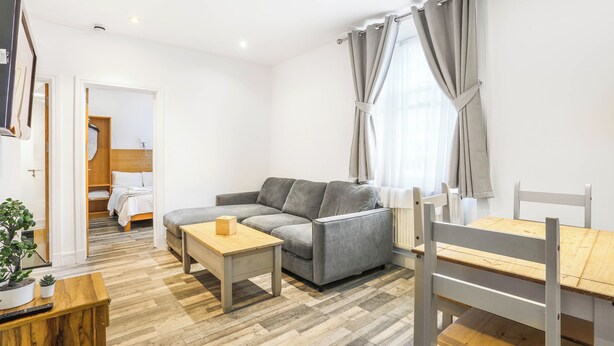 Een moderne woonkamer met een bank, een houten tafel en een eethoek met stoelen.