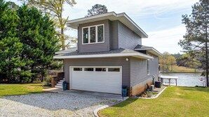 A two-story house with a garage, a covered porch, and a view of a lake. - Greenwood Group Retreat w/ Large Private Dock! (Greenwood)