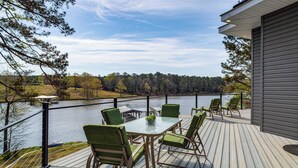 A deck with a table and chairs overlooking a lake, surrounded by trees. - Greenwood Group Retreat w/ Large Private Dock! (Greenwood)