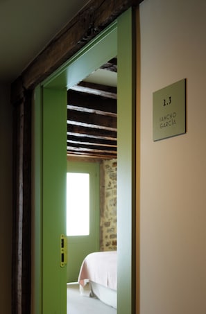 Una habitación con una cama, una puerta verde y un letrero en la pared.