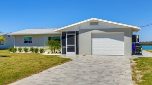 A modern house with a garage, a paved driveway, and a small lawn with a palm tree. - Home w/ Views & Dock on Lemon Bay Aquatic Preserve (Englewood)