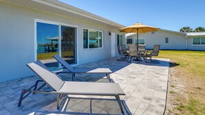 A patio with lounge chairs, a table, and an umbrella. - Home w/ Views & Dock on Lemon Bay Aquatic Preserve (Englewood)