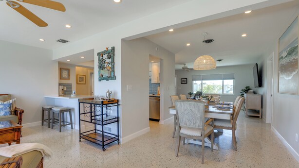 A spacious living area with a dining table, chairs, a ceiling fan, and a kitchen in the background. - Home w/ Views & Dock on Lemon Bay Aquatic Preserve (Englewood)