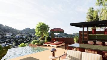 A rooftop terrace with a pool, lounge chairs, and a dining area overlooking a mountainous landscape.