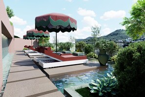 Zona junto a la piscina con asientos, sombrillas y una fuente.