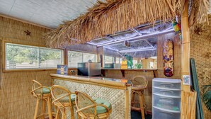 Un restaurante con techo de paja, paredes de bambú y mobiliario de mimbre.