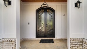 Una doble puerta con intrincados detalles de metalería, techo de madera y base de ladrillo.