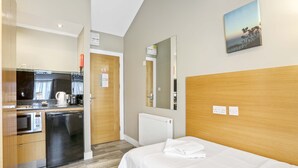 Ein Hotelzimmer mit Bett, einer kleinen Küchenzeile, einer Mikrowelle, einer Kaffeemaschine und Meerblick.