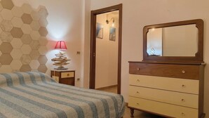 Quarto com cama, penteadeira, abajur e parede com padrões hexagonais.