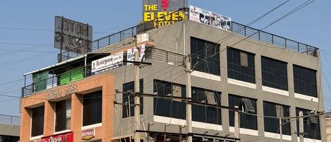 Un edificio de varios pisos con varios letreros, incluyendo 'The 7 Eleven' y 'ISKON Outfits'.