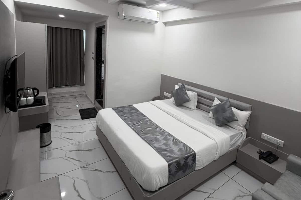 A modern hotel room with a large bed, a TV, a desk, and a bathroom.