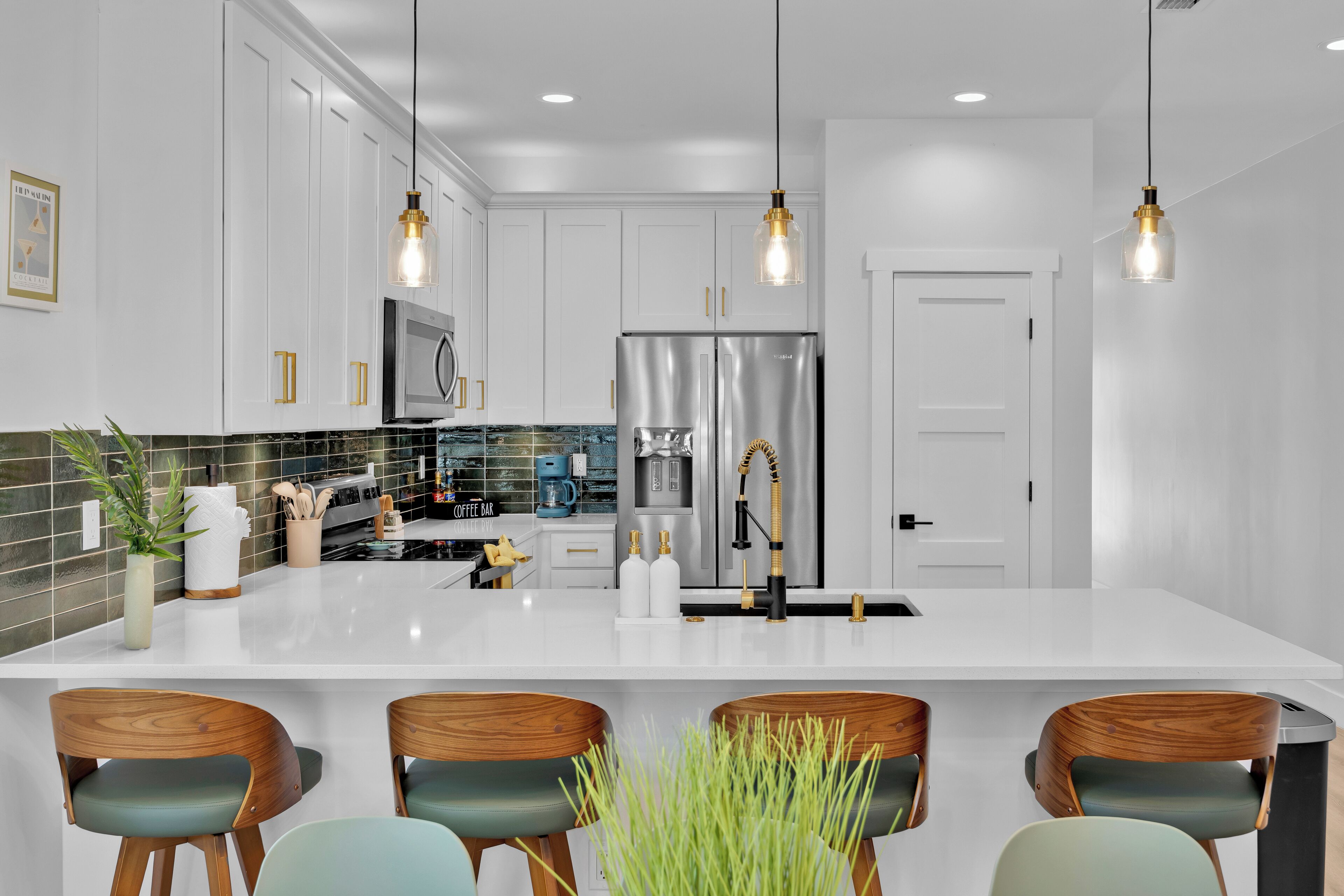 A modern kitchen with white cabinets, stainless steel appliances, and a central island with bar stools.