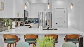 A modern kitchen with white cabinets, stainless steel appliances, and a central island with bar stools.