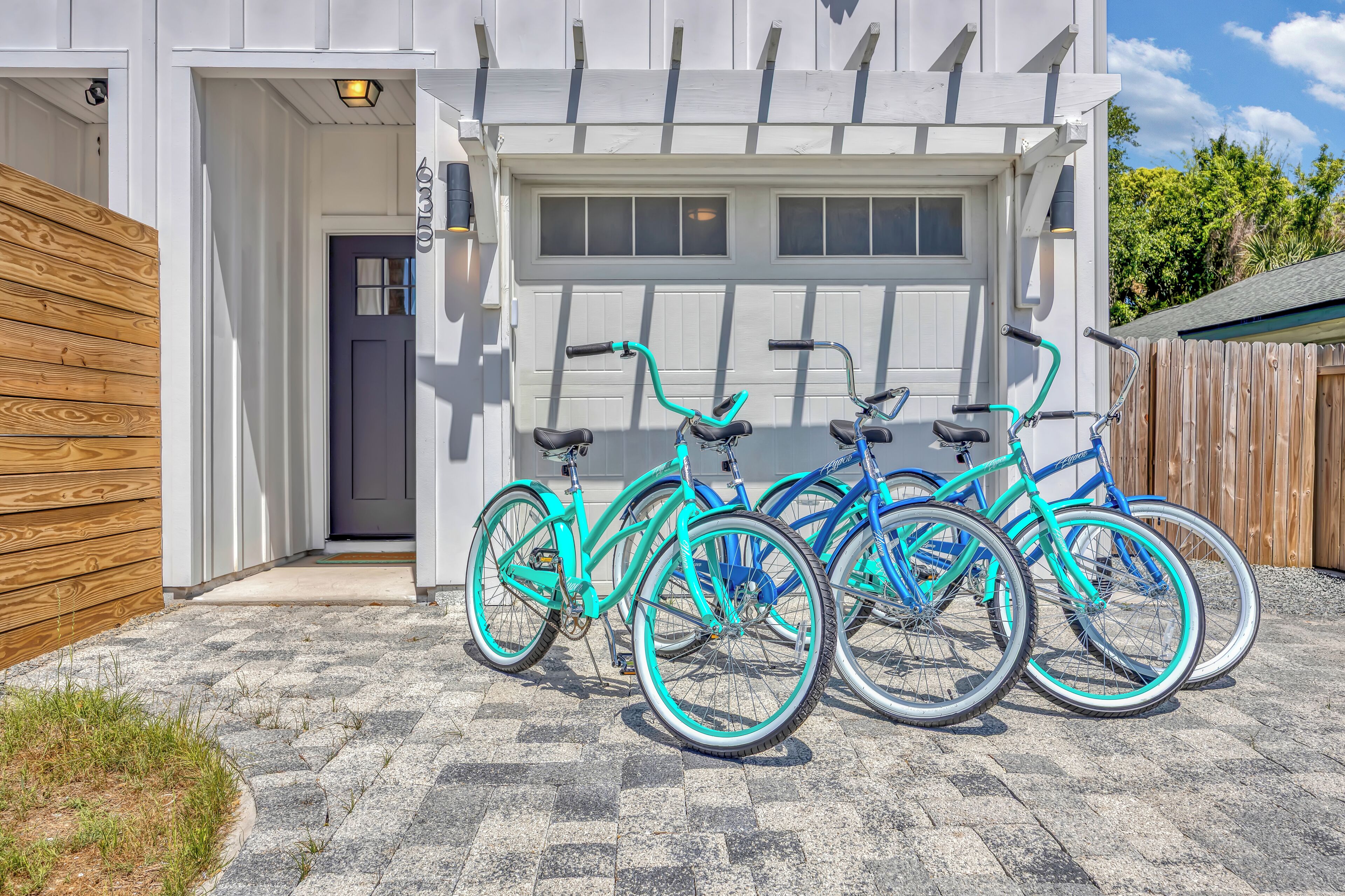 Une maison avec une porte de garage, une clôture en bois et trois vélos garés à l’extérieur.