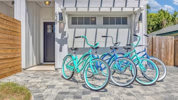 Une maison avec une porte de garage, une clôture en bois et trois vélos garés à l’extérieur.