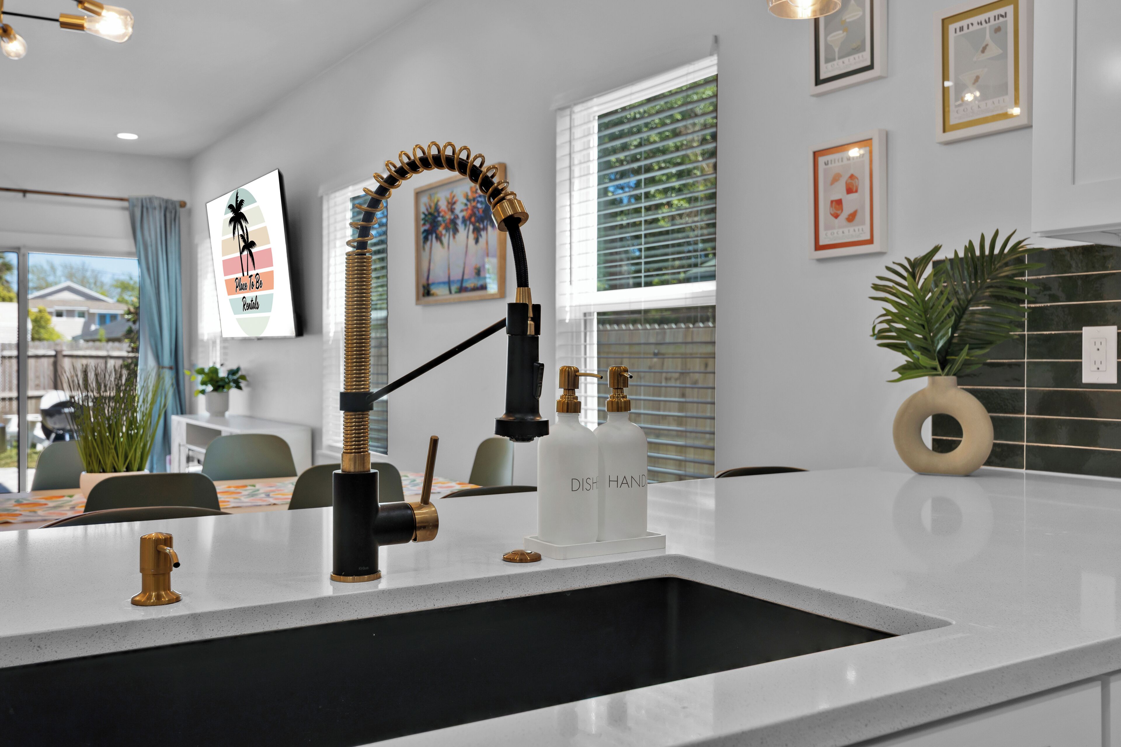 A modern kitchen with a white countertop, a black faucet, and a backsplash.