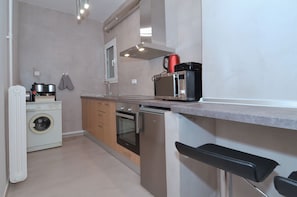 A compact kitchen with a washing machine, oven, microwave, and a coffee maker. - Studio in the heart of Athens (Athens)