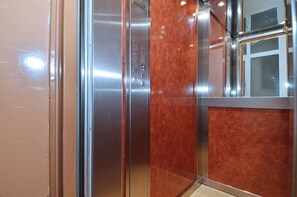 An elevator interior with metallic walls, a control panel, and a glass door. - Studio in the heart of Athens (Athens)