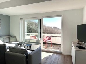 Ein modernes Wohnzimmer mit einer Couch, einem kleinen Tisch und einem Fernseher.