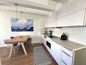 Eine moderne Küche mit weißen Schränken, einem Holzespeisetisch und einem schwarzen Wasserkocher.