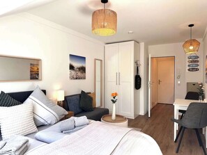 Camera da letto moderna con un letto, comodino, lampada e vista sulla spiaggia dalla finestra.