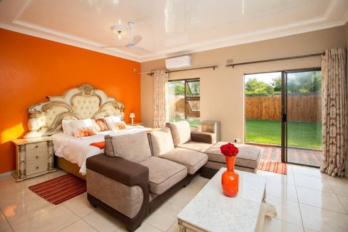 Ein Schlafzimmer mit Bett, einer Couch, einem Couchtisch und Blick ins Freie.