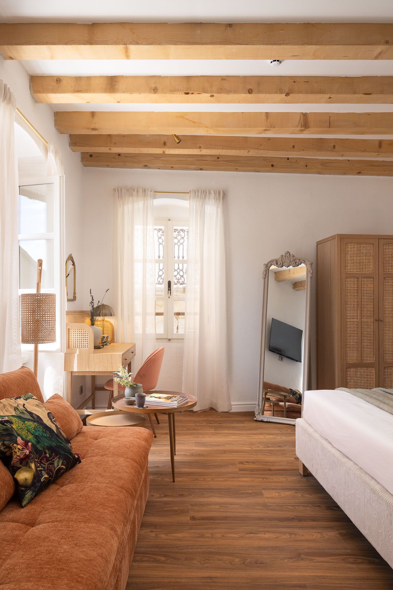 A cozy room with a wooden ceiling, a desk with a chair, a bed, and a wardrobe.