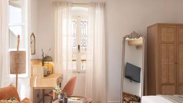 A cozy room with a wooden ceiling, a desk with a chair, a bed, and a wardrobe.