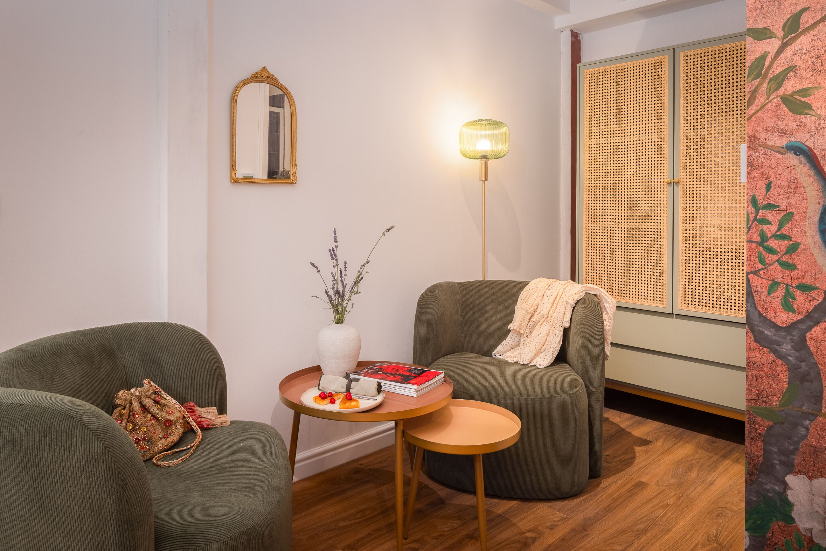 Un salon chaleureux avec un canapé, une petite table ornée d’un vase et de quelques livres, et une lampe.