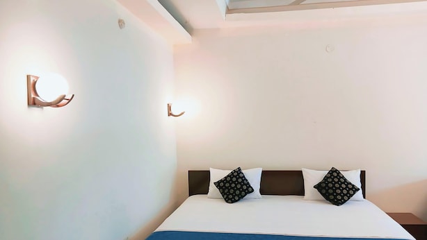 A hotel room with a bed, two wall-mounted light fixtures, and a ceiling vent. - Moon View Homestay (Guwahati)
