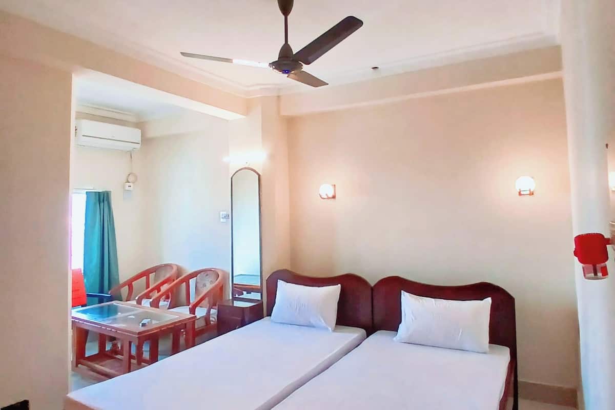 A hotel room with a bed, a ceiling fan, a mirror, and a window.