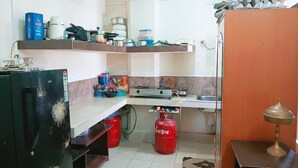 A compact kitchen with a gas stove, a sink, and a countertop with various kitchen items. - Moon View Homestay (Guwahati)