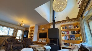 Ein gemütliches Wohnzimmer mit Kamin, Bücherregalen und einem großen Fenster.
