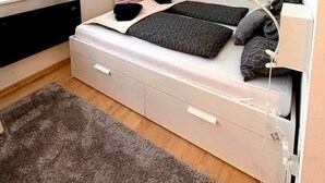 Una camera da letto con un letto, una televisione, una scrivania e una finestra con tende.