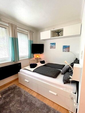 A bedroom with a bed, a TV, a desk, and a window with curtains. - Apartment Schladming with sauna and pool (Schladming)