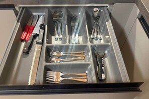 A drawer with utensils including a knife, forks, spoons, and a bottle opener. - Timber Studio Schladming - Alpine Corner (Schladming)